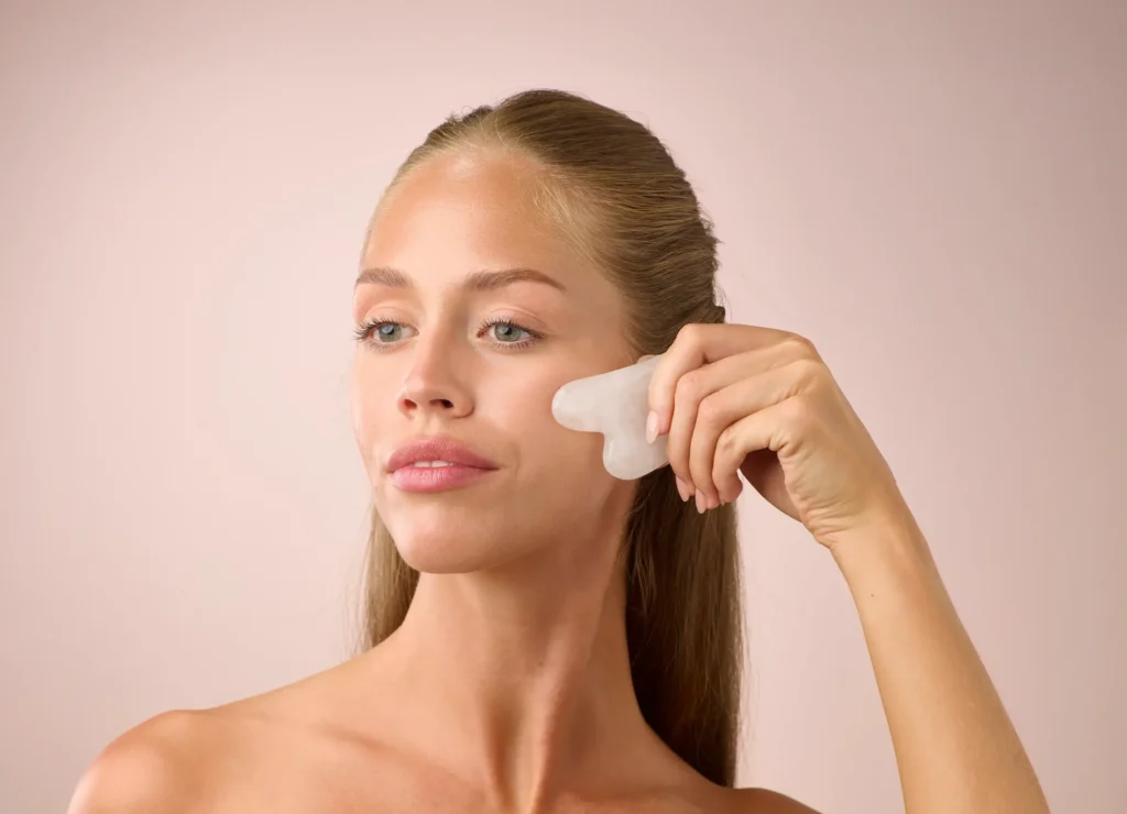 A woman doing her skincare using a gua sha