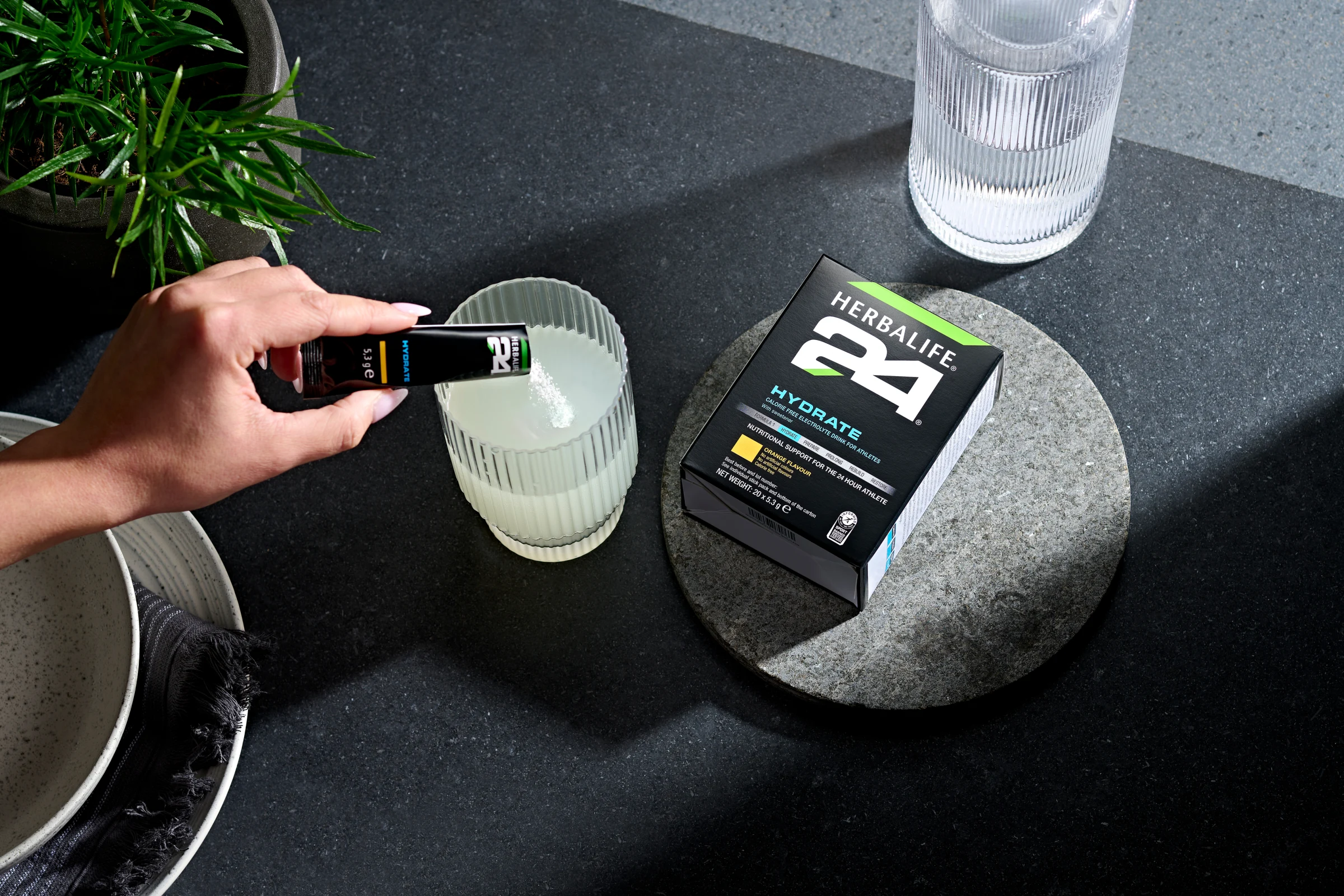 Person pouring Herbalife hydrate sachet into water for hot weather hydration